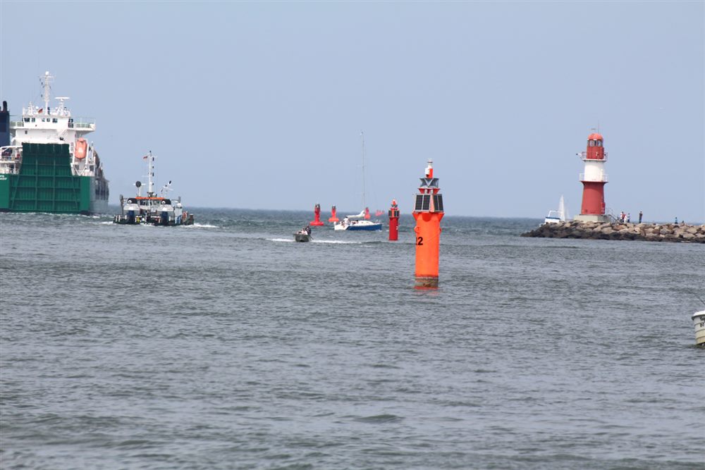 Foto: Hafeneinfahrt mit roten Leuchttonnen und Molenfeuerturm