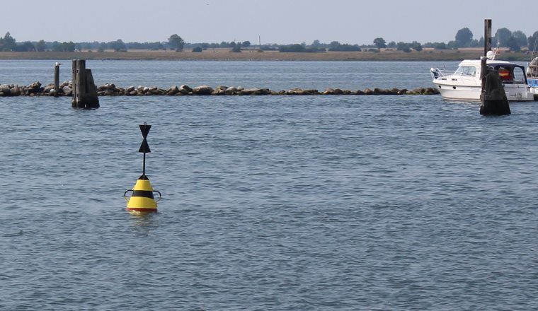 Foto: Westkardinaltonne gelb-schwarz-gelb vor einem Yachthafen